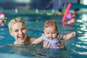 Happy mom is relaxing in swimming pool with little baby girl. Rest and relaxation.